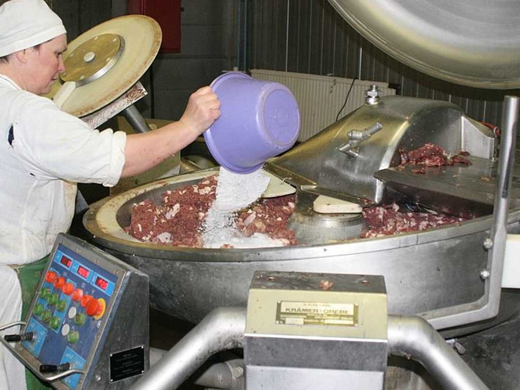 Picture of a woman stirring a huge cauldron in a sausage factory
