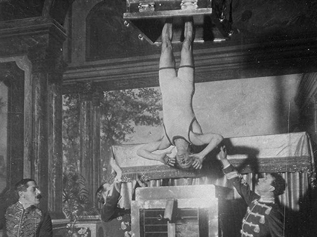 Houdini, in chains, being lowered upside down into a tank of water